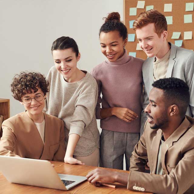 Diverse group of professionals collaborating around a laptop