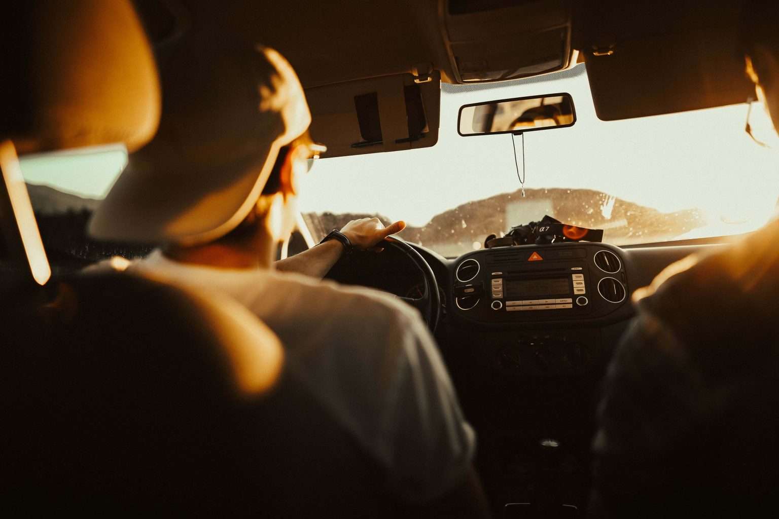 Driver and passenger in car at sunset