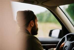 Man in turban driving car on rainy day