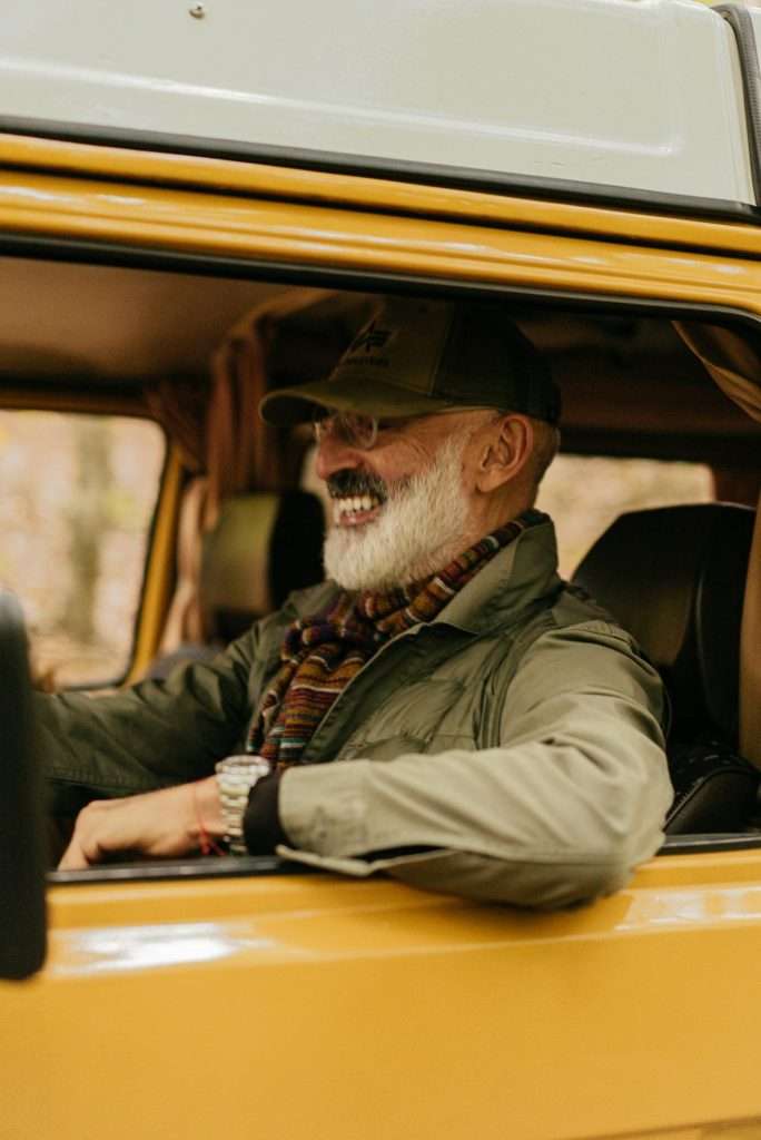 Smiling elderly man driving a yellow vintage car