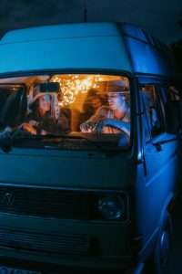 Friends celebrating with sparklers in vintage van at night