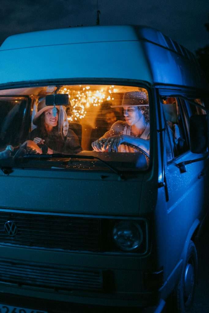 Friends celebrating with sparklers in vintage van at night