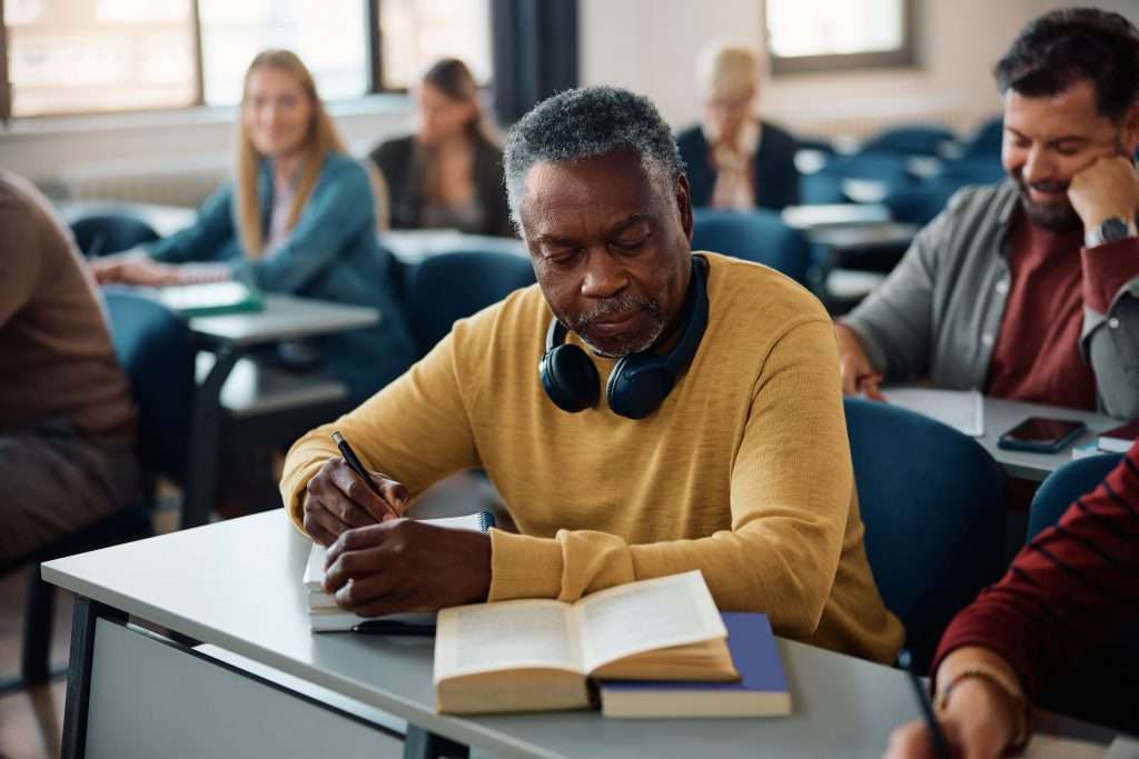 Senior man studying in classroom with young adults