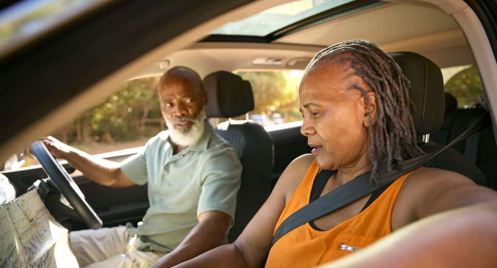Senior couple navigating road trip in car